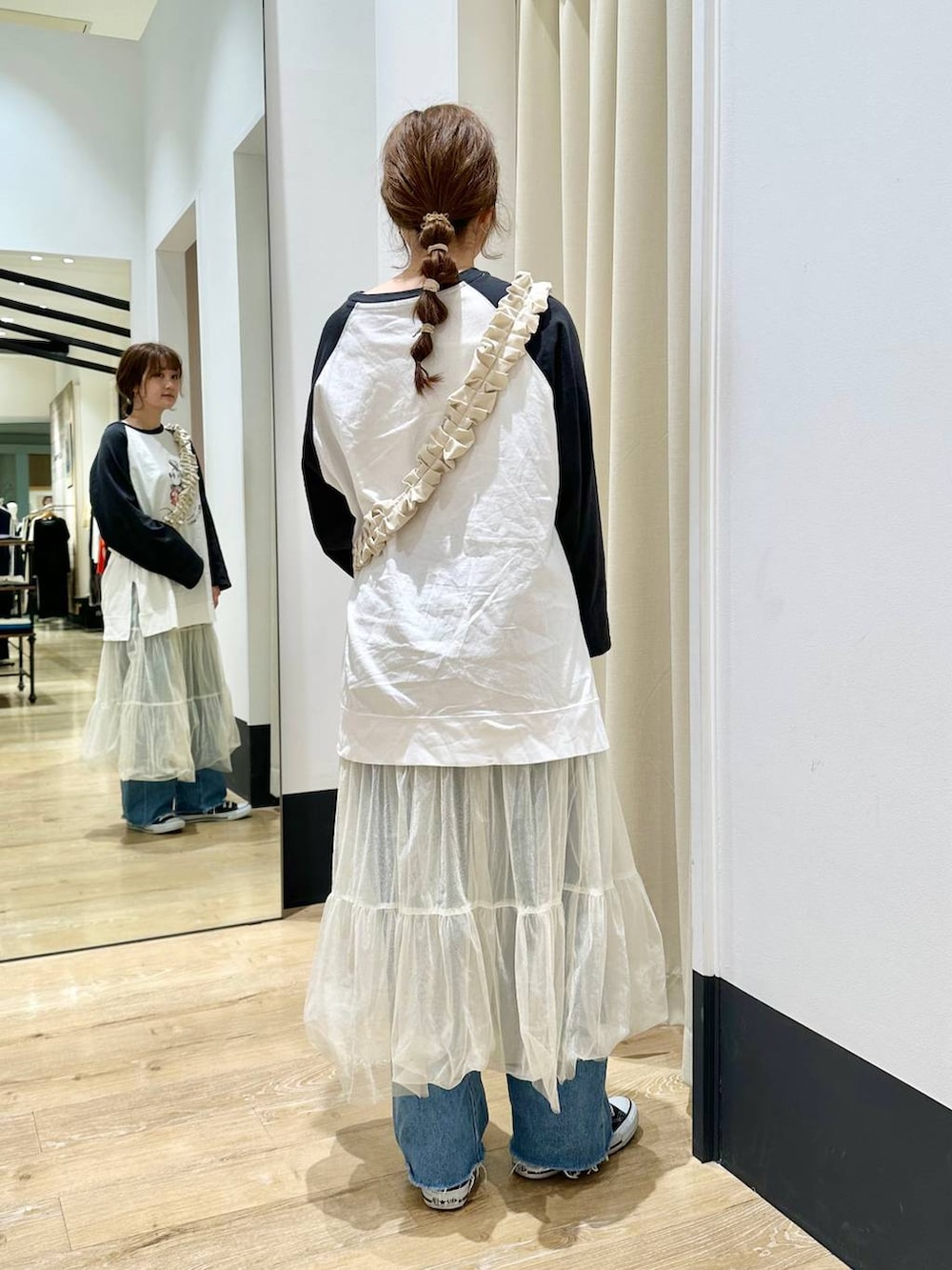 ホワイト系のスカート、ブラック系のTシャツ/カットソー、ブルー系のデニムパンツを着用したレディースの春コーディネートの5枚目の写真