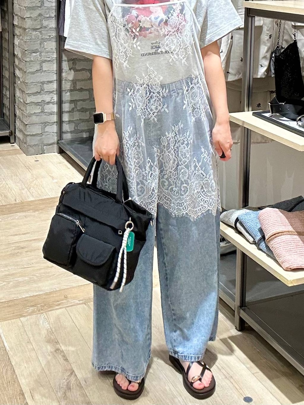 ブルー系のデニムパンツ、ブラック系のトートバッグ、ブラウン系のサンダルを着用したレディースの春コーディネートの5枚目の写真