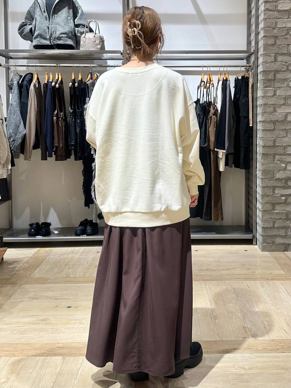 ブラック系のショルダーバッグ、ブラウン系のスカート、ブラック系のブーツを着用したレディースの秋コーディネートの3枚目の写真