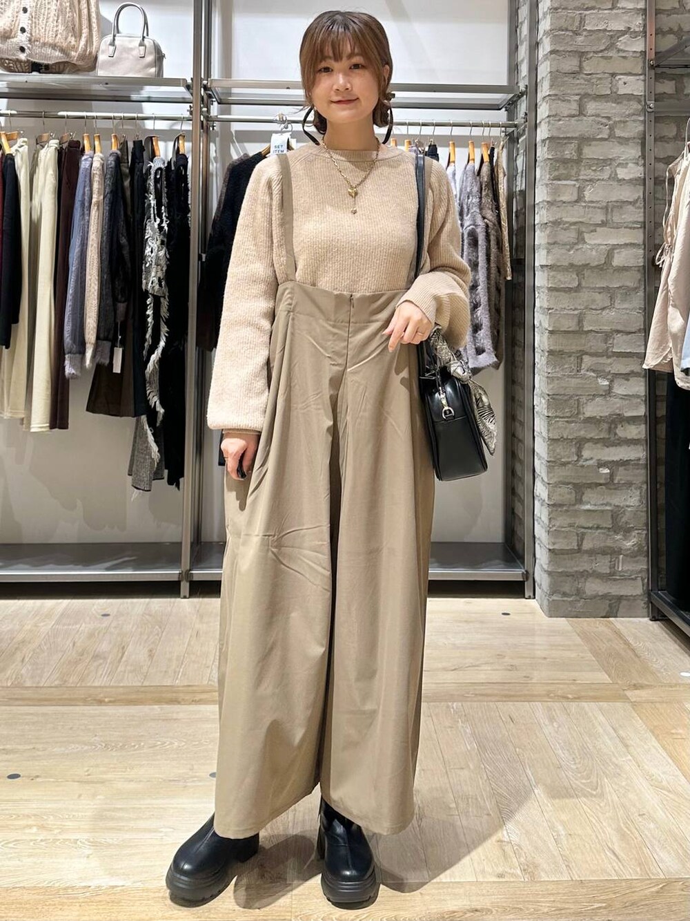 ベージュ系のニット/セーター、ブラック系のボストンバッグ、ブラック系のブーツを着用したレディースの秋コーディネートの2枚目の写真