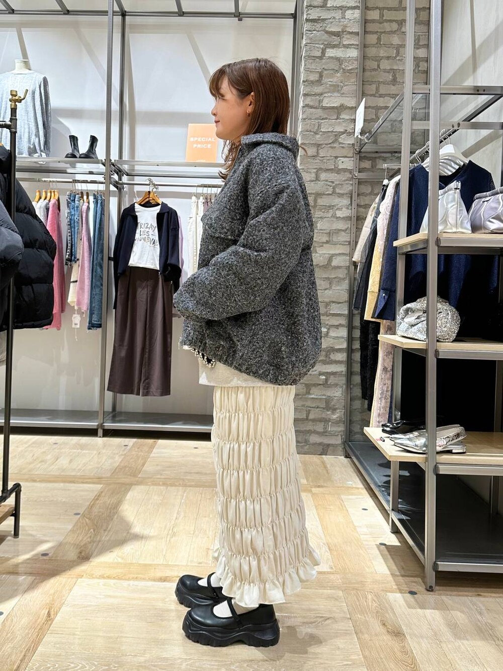 ブラック系のスニーカー、ホワイト系のスカート、グレー系のブルゾンを着用したレディースの秋コーディネートの2枚目の写真