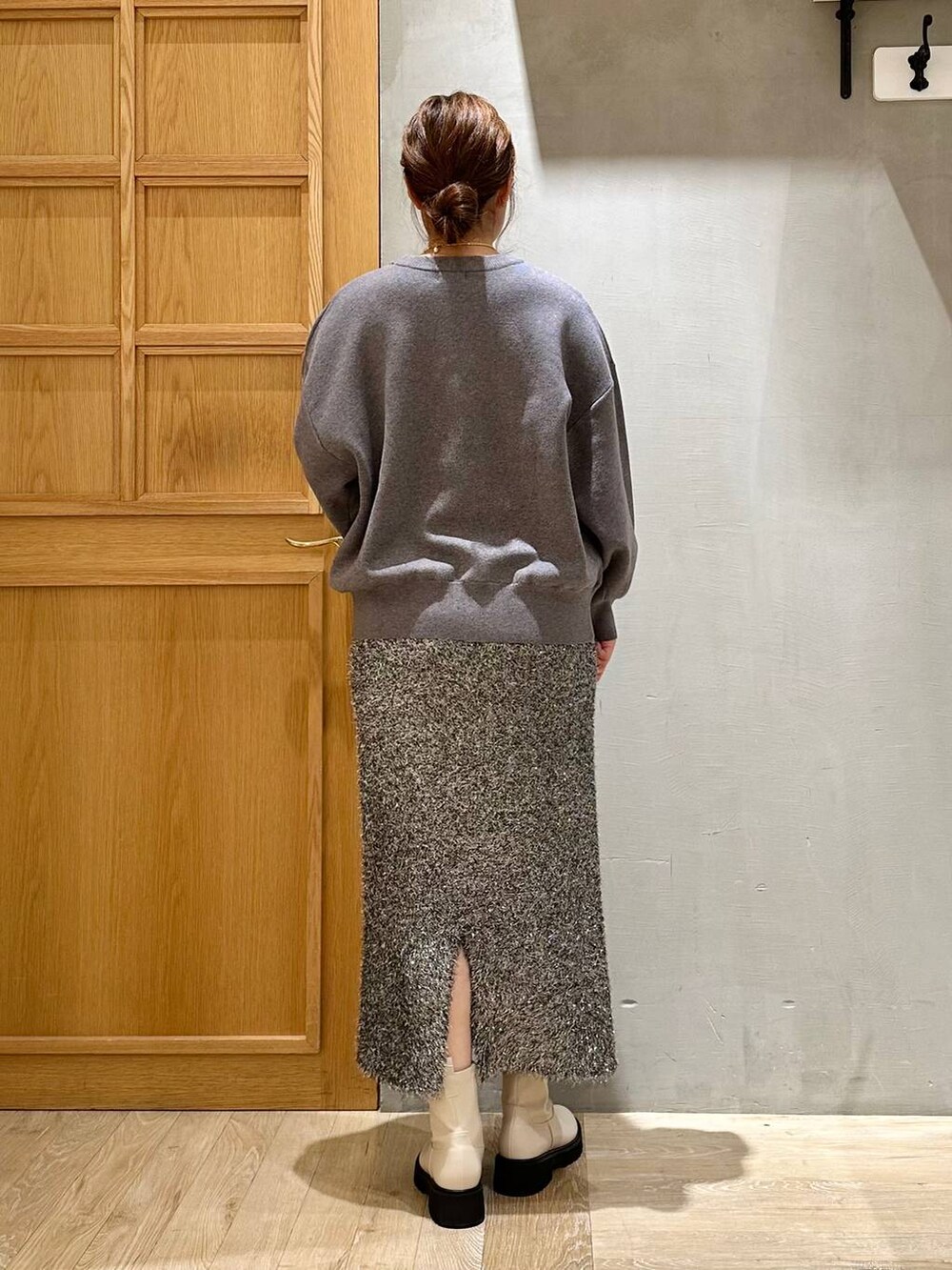 ホワイト系のブーツ、グレー系のニット/セーター、ブラック系のスカートを着用したレディースの冬コーディネートの4枚目の写真