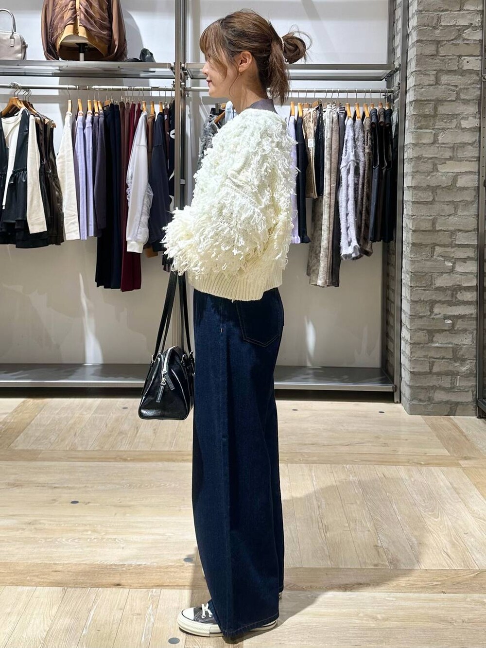 ブルー系のデニムパンツ、グレー系のニット/セーター、ブラック系のボストンバッグを着用したレディースの秋コーディネートの3枚目の写真