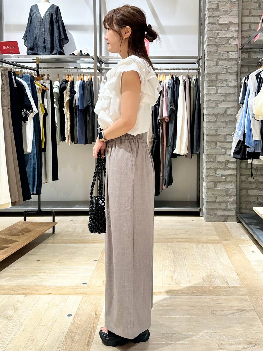 ベージュ系のその他パンツ、ブラック系のサンダル、ブラック系のハンドバッグを着用したレディースの夏コーディネートの2枚目の写真