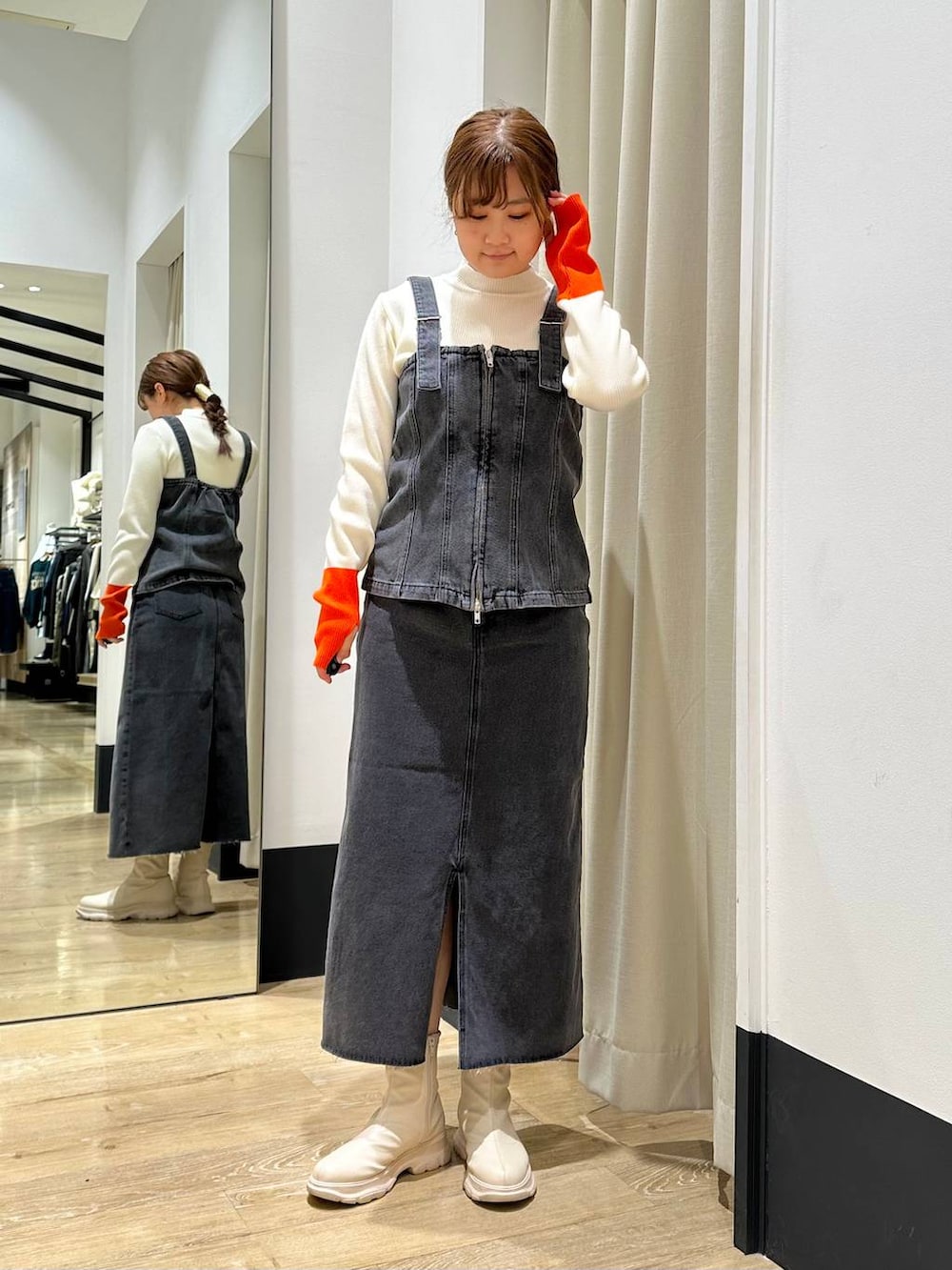 ブラック系のベスト、ブラック系のスカート、ホワイト系のニット/セーターを着用したレディースの冬コーディネートの2枚目の写真