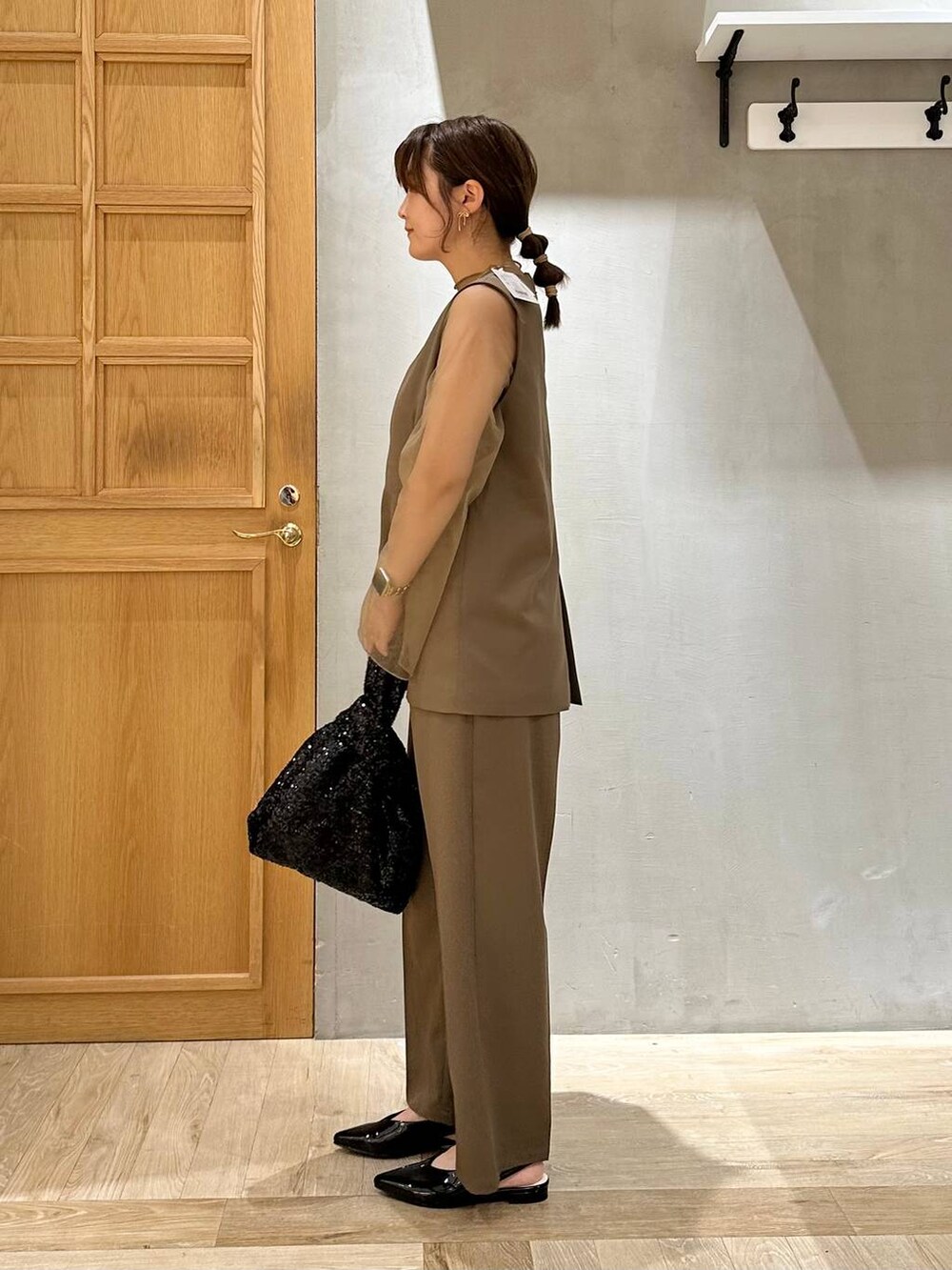 ブラック系のその他シューズ、グリーン系のパンツドレス、ブラック系のハンドバッグを着用したレディースの秋コーディネートの2枚目の写真