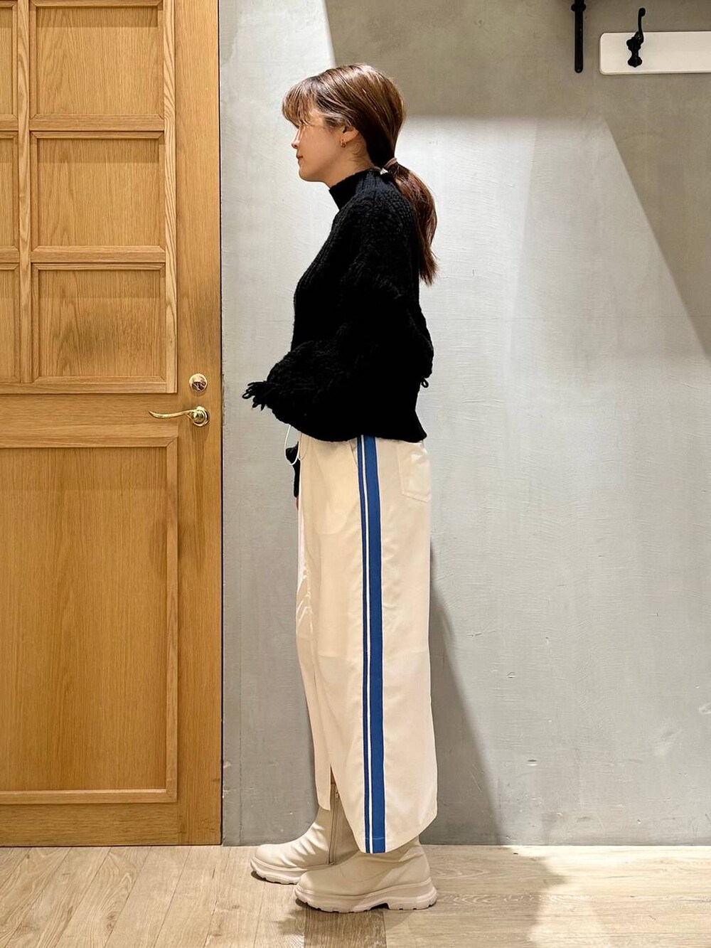 ブラック系のニット/セーター、ホワイト系のブーツ、ホワイト系のスカートを着用したレディースの冬コーディネートの3枚目の写真