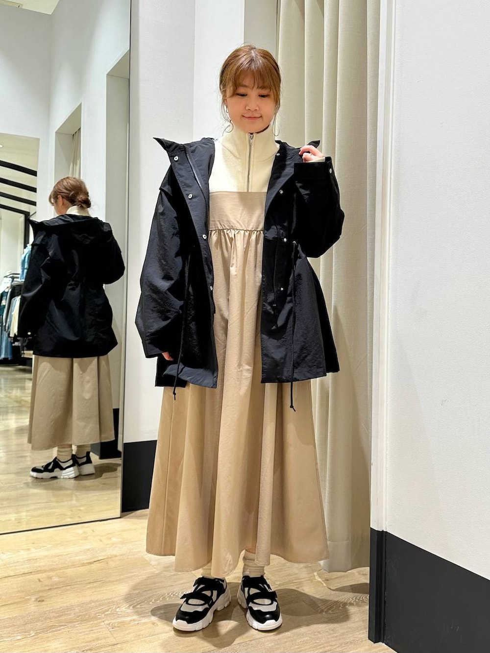 ベージュ系のワンピース、ブラック系のその他アウター、ホワイト系のスニーカーを着用したレディースの冬コーディネートの2枚目の写真