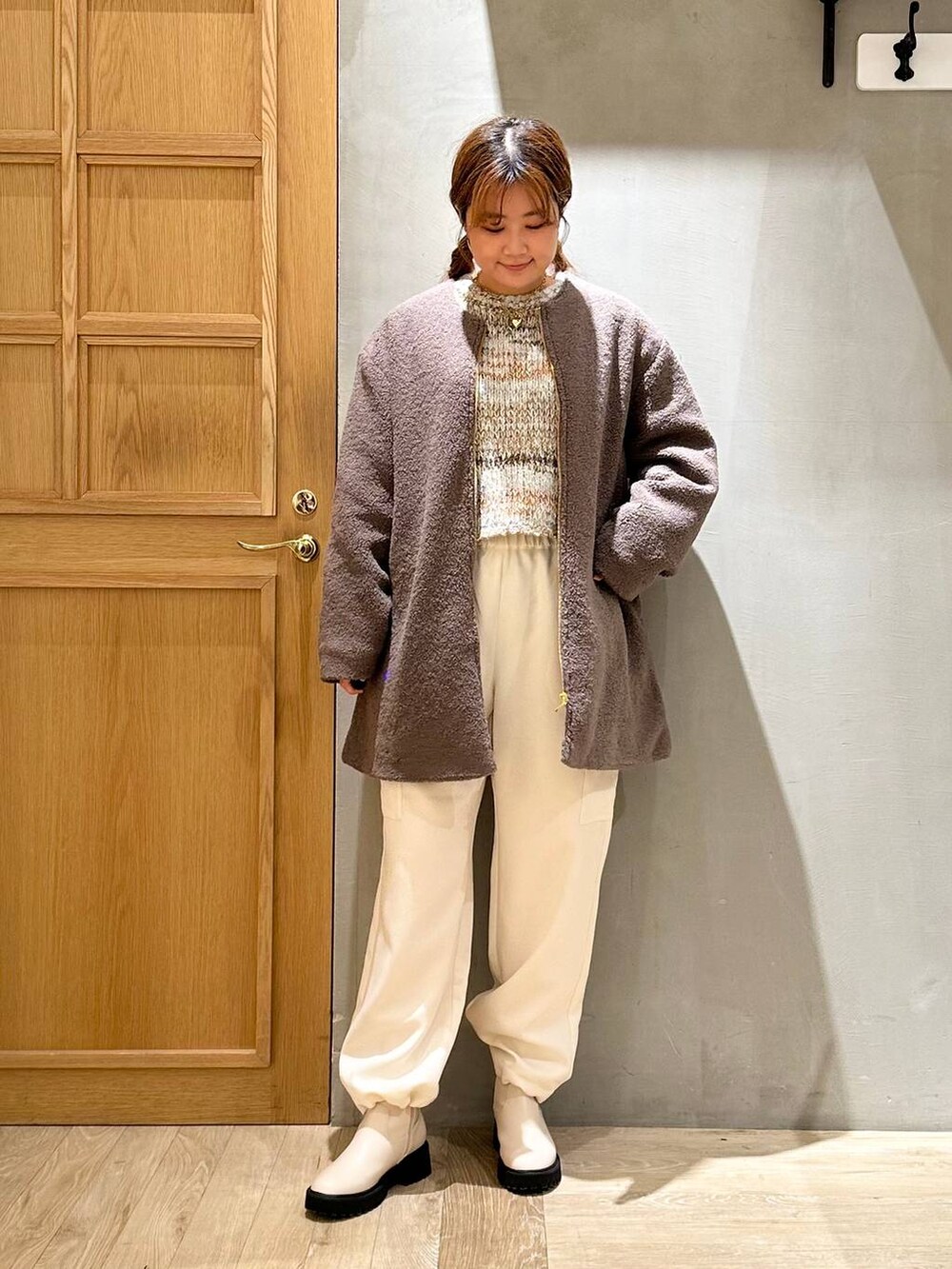 ブラウン系のノーカラーコート、ホワイト系のブーツ、ホワイト系のショルダーバッグを着用したレディースの秋コーディネートの2枚目の写真