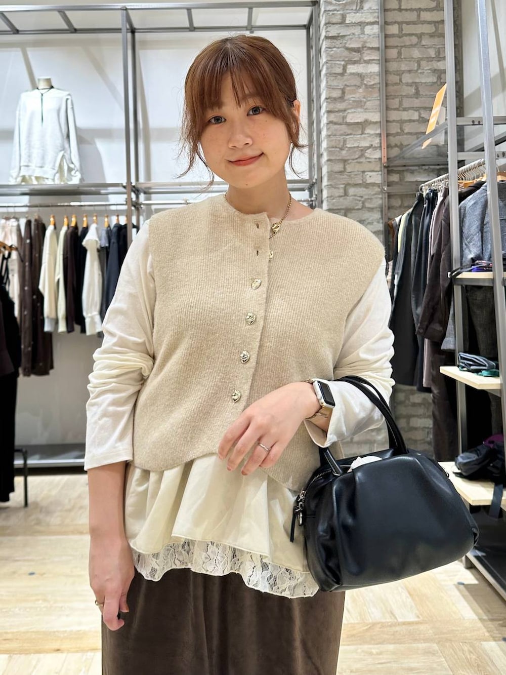ブラック系のパンプス、ブラック系のショルダーバッグ、ベージュ系のベストを着用したレディースの秋コーディネートの4枚目の写真