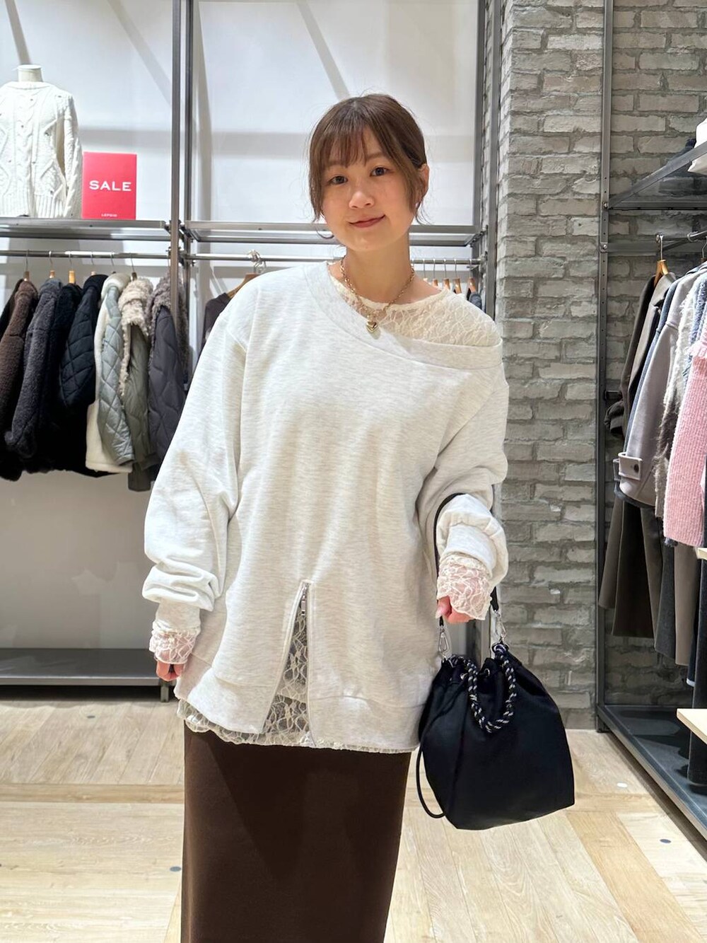 ブラック系のショルダーバッグ、ブラウン系のスカート、ブラック系のサンダルを着用したレディースの冬コーディネートの3枚目の写真