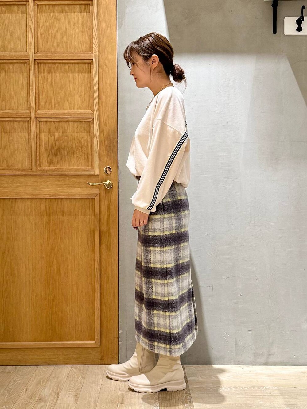 グレー系のスカート、ブラック系のショルダーバッグ、ホワイト系のブーツを着用したレディースの冬コーディネートの3枚目の写真