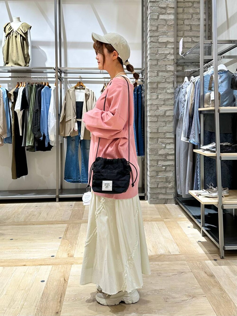 ブラック系のショルダーバッグ、ピンク系のTシャツ/カットソー、ベージュ系のスニーカーを着用したレディースの春コーディネートの3枚目の写真