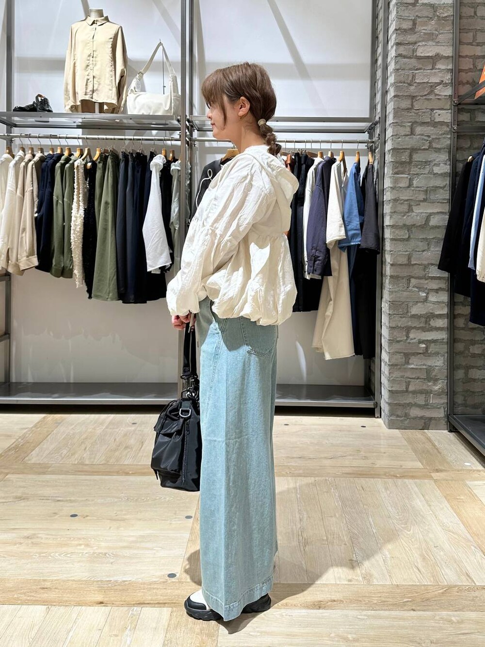 ブラック系のショルダーバッグ、ピンク系のTシャツ/カットソー、ブルー系のデニムパンツを着用したレディースの春コーディネートの2枚目の写真