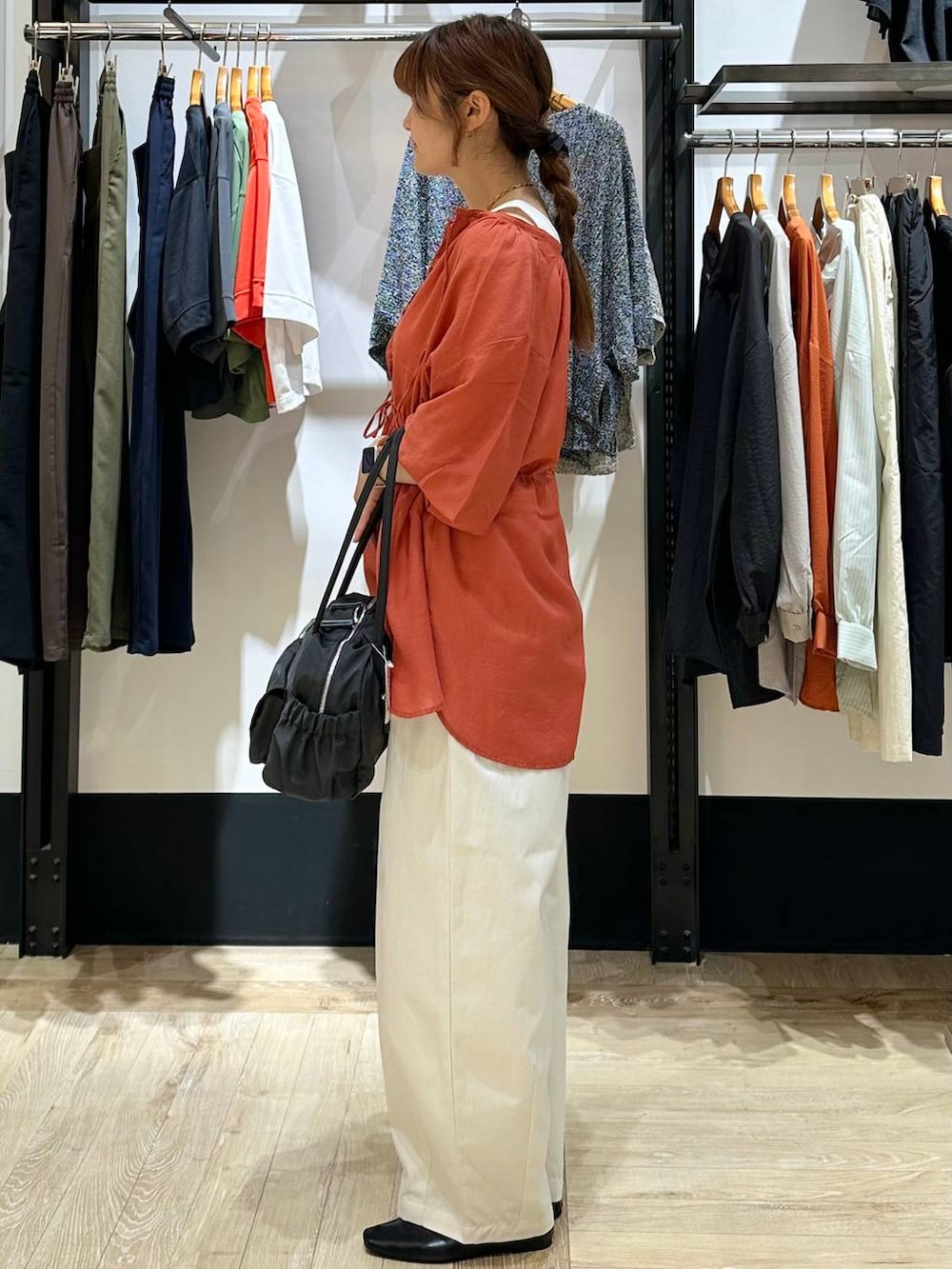 ブラック系のパンプス、オレンジ系のシャツ/ブラウス、グレー系のボストンバッグを着用したレディースの春コーディネートの2枚目の写真