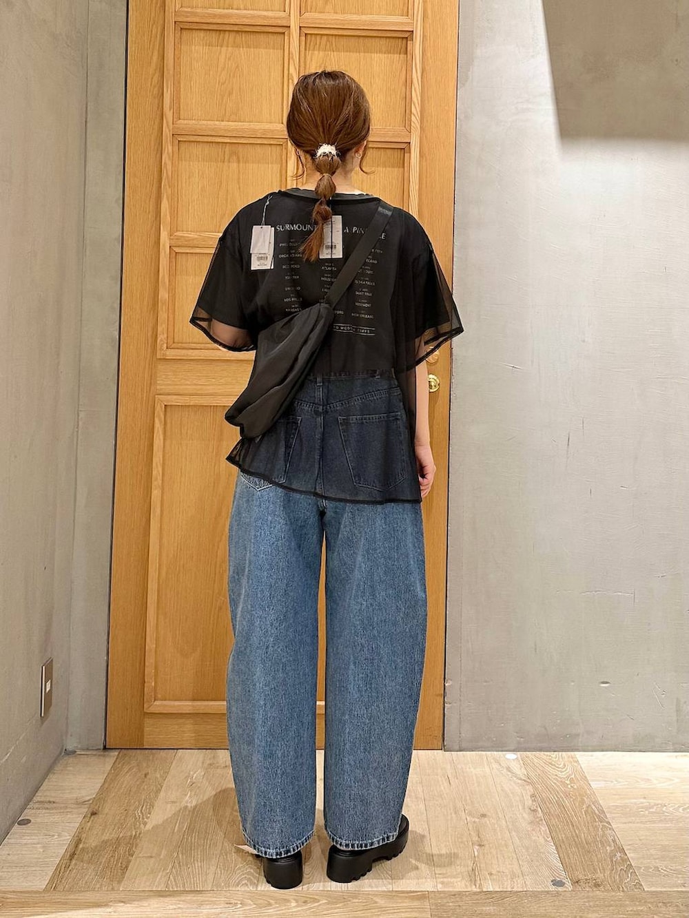 ブルー系のデニムパンツ、ブラック系のショルダーバッグ、ブラック系のTシャツ/カットソーを着用したレディースの春コーディネートの3枚目の写真