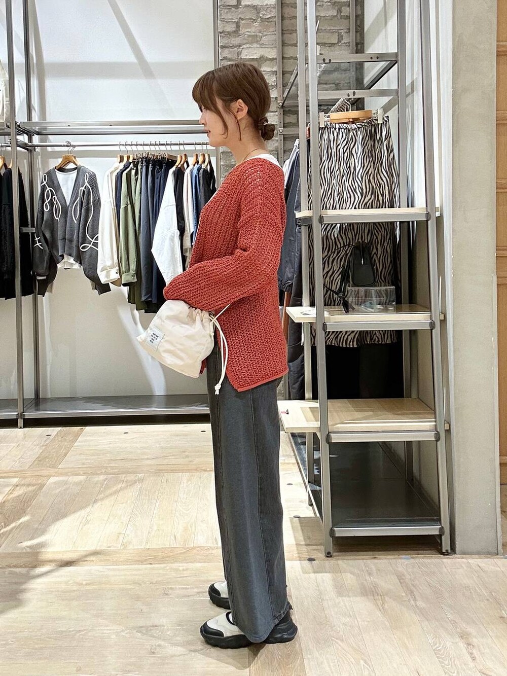 レッド系のニット/セーター、ホワイト系のショルダーバッグ、ホワイト系のスニーカーを着用したレディースの春コーディネートの2枚目の写真