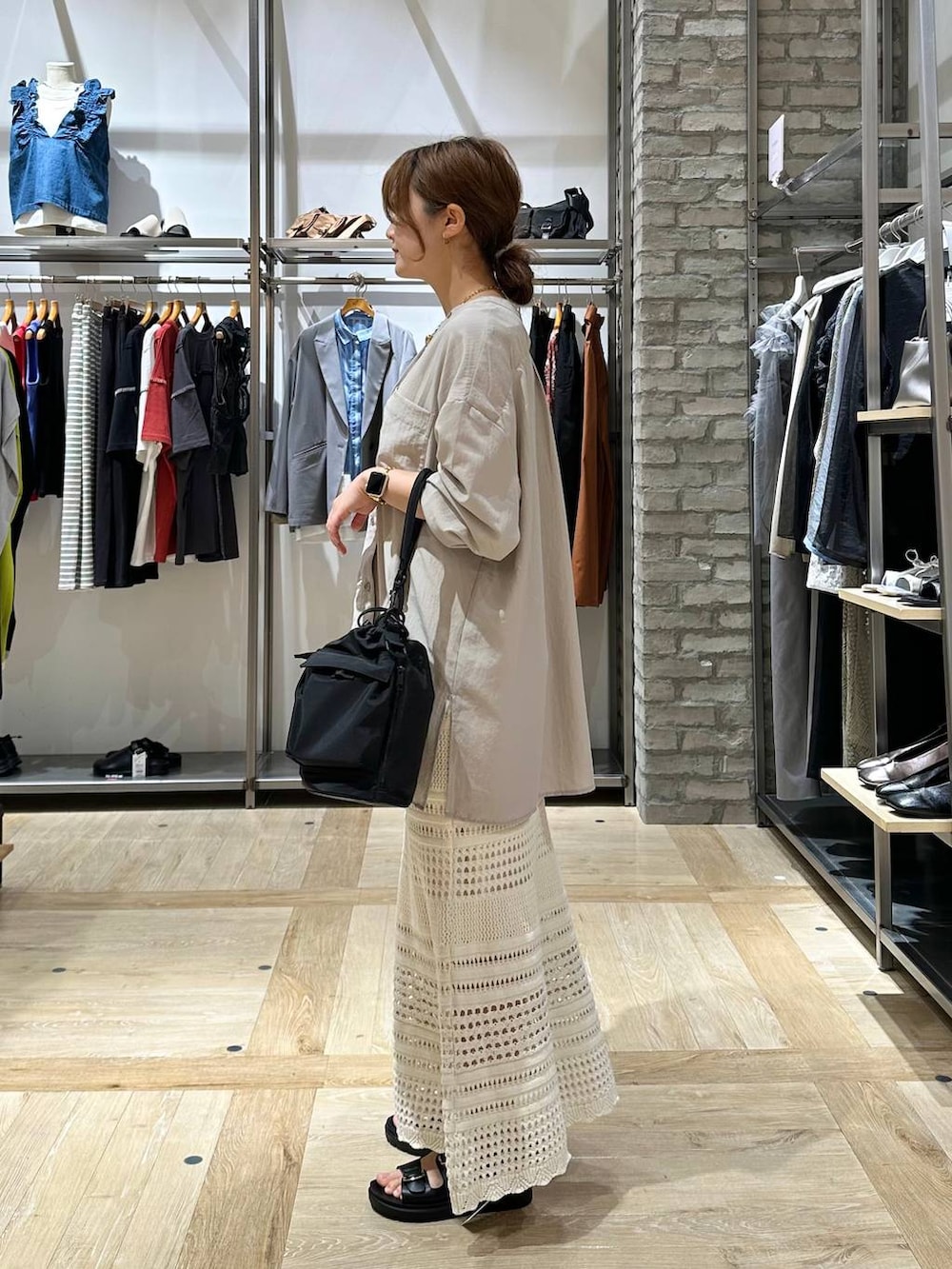 ブラック系のショルダーバッグ、ホワイト系のタンクトップ、ベージュ系のチュニックを着用したレディースの春コーディネートの2枚目の写真