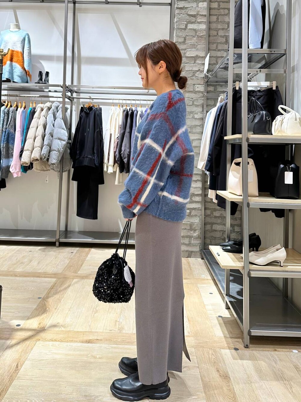 ブラック系のショルダーバッグ、グレー系のスカート、ブラック系のブーツを着用したレディースの冬コーディネートの2枚目の写真