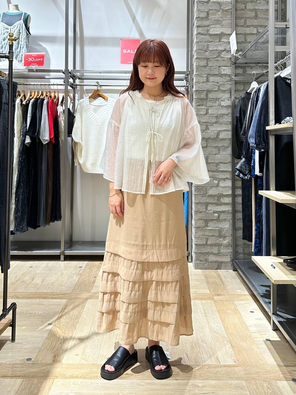 ベージュ系のスカート、ホワイト系のシャツ/ブラウス、ブラック系のサンダルを着用したレディースの夏コーディネートの2枚目の写真