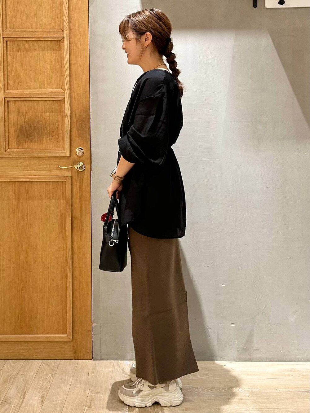 ブラック系のシャツ/ブラウス、ブラウン系のスカート、ブラック系のボストンバッグを着用したレディースの秋コーディネートの2枚目の写真