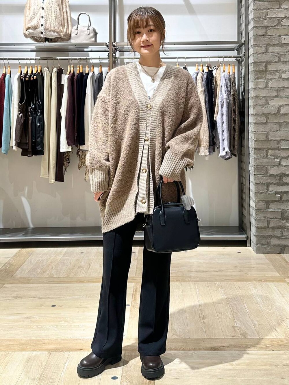ブラック系のその他パンツ、ブラック系のボストンバッグ、ブラウン系のカーディガン/ボレロを着用したレディースの秋コーディネートの2枚目の写真