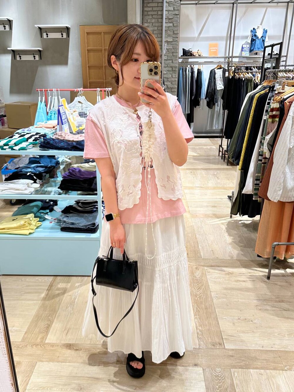 ホワイト系のベスト、ブラック系のショルダーバッグ、ブラック系のサンダルを着用したレディースの春コーディネートの3枚目の写真