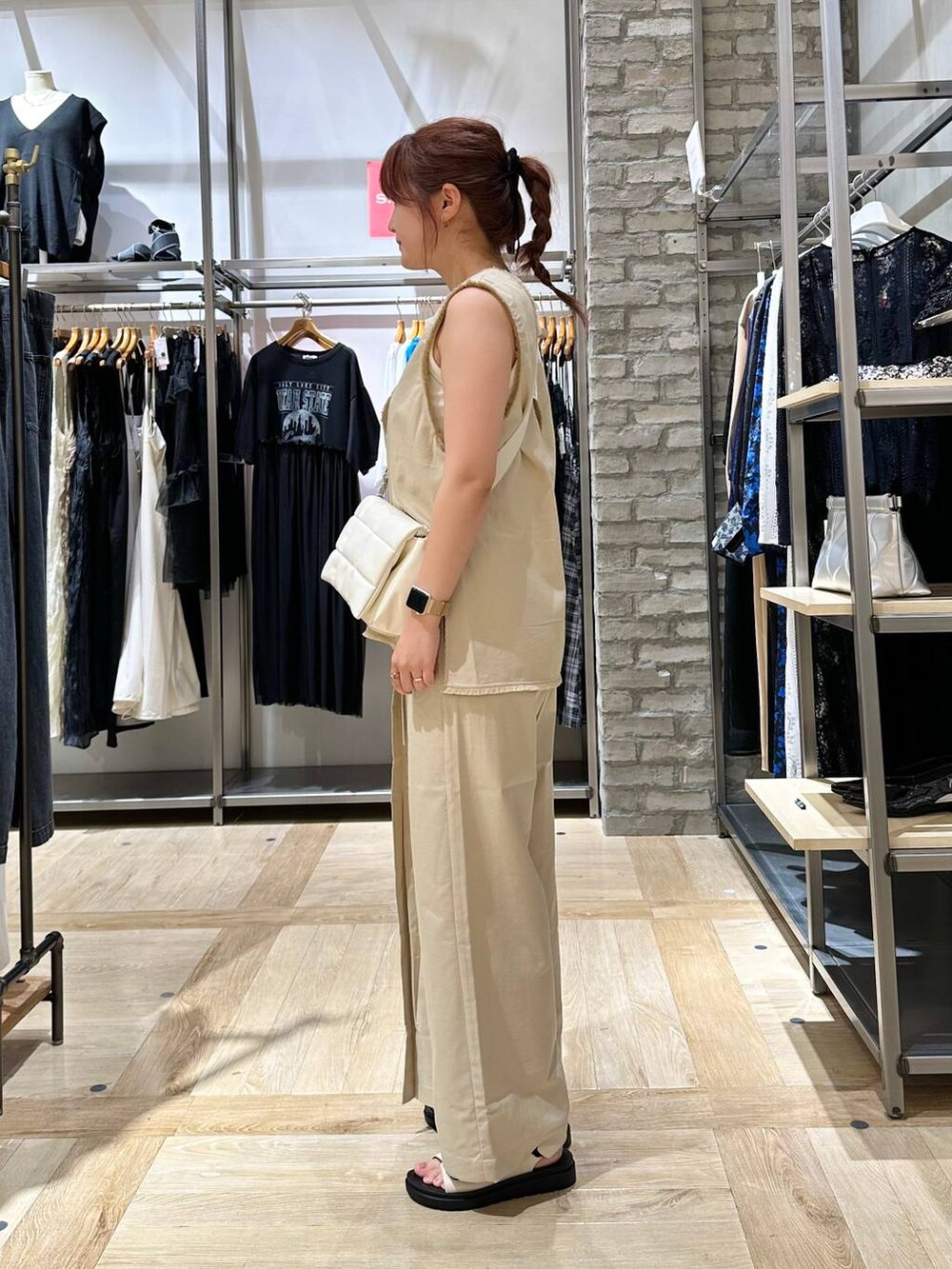 ホワイト系のショルダーバッグ、ホワイト系のベスト、ホワイト系のサンダルを着用したレディースの夏コーディネートの2枚目の写真