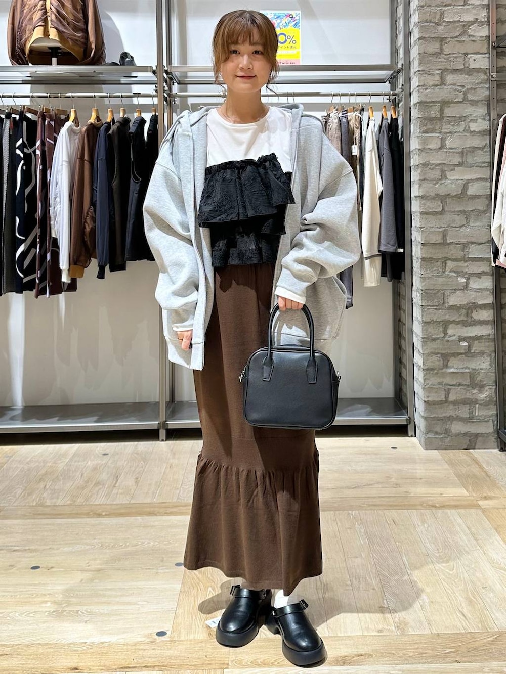 ブラウン系のスカート、ホワイト系のTシャツ/カットソー、ブラック系のサンダルを着用したレディースの秋コーディネートの2枚目の写真