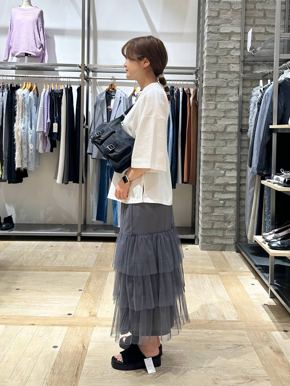 ホワイト系のTシャツ/カットソー、ブラック系のショルダーバッグ、ブラック系のサンダルを着用したレディースの春コーディネートの2枚目の写真