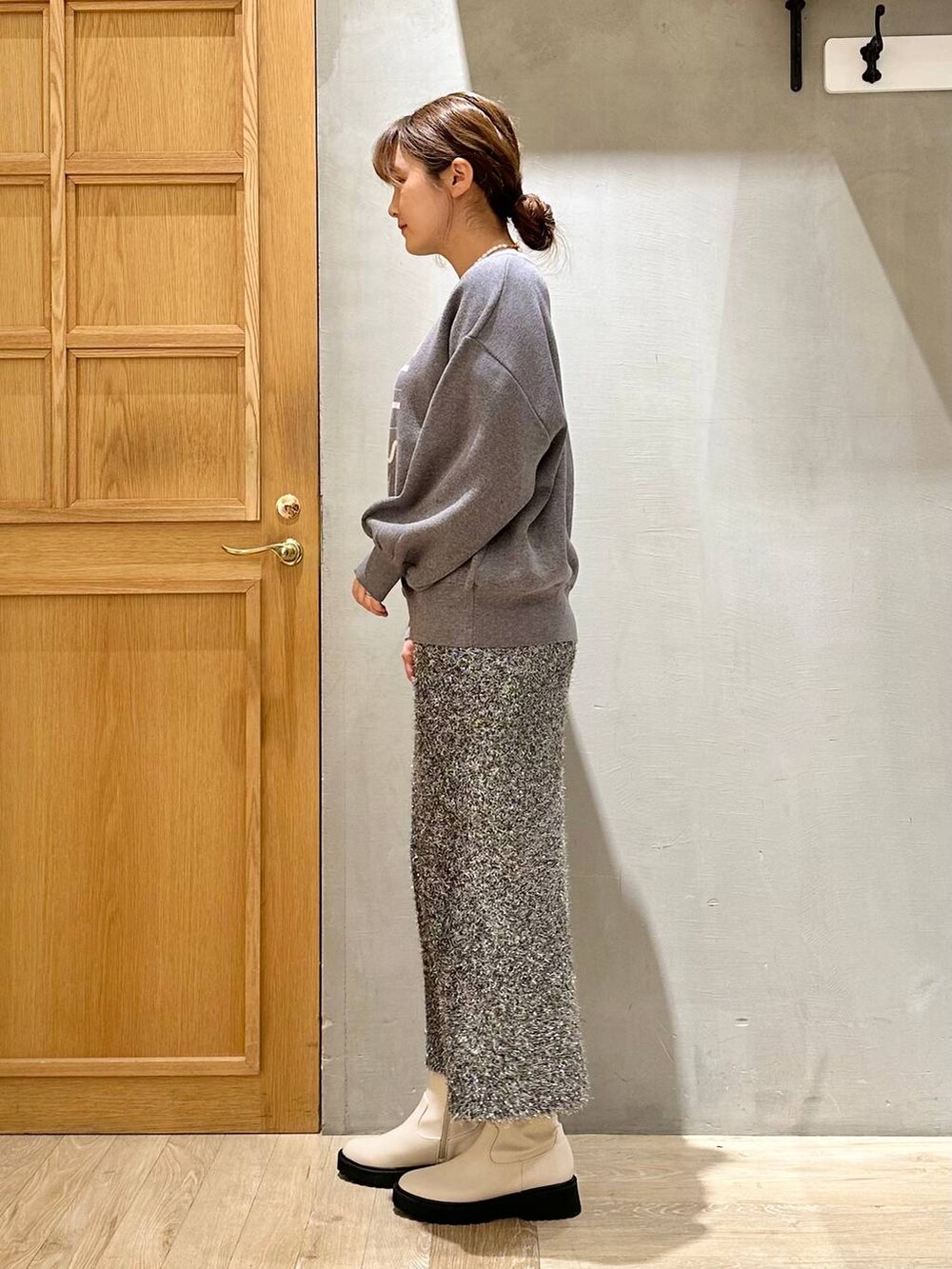 ホワイト系のブーツ、グレー系のニット/セーター、ブラック系のスカートを着用したレディースの冬コーディネートの3枚目の写真