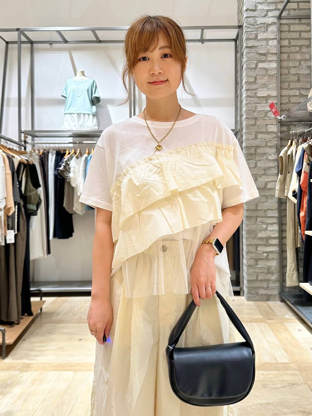 ホワイト系のサンダル、ブラック系のハンドバッグ、ホワイト系のTシャツ/カットソーを着用したレディースの夏コーディネートの4枚目の写真