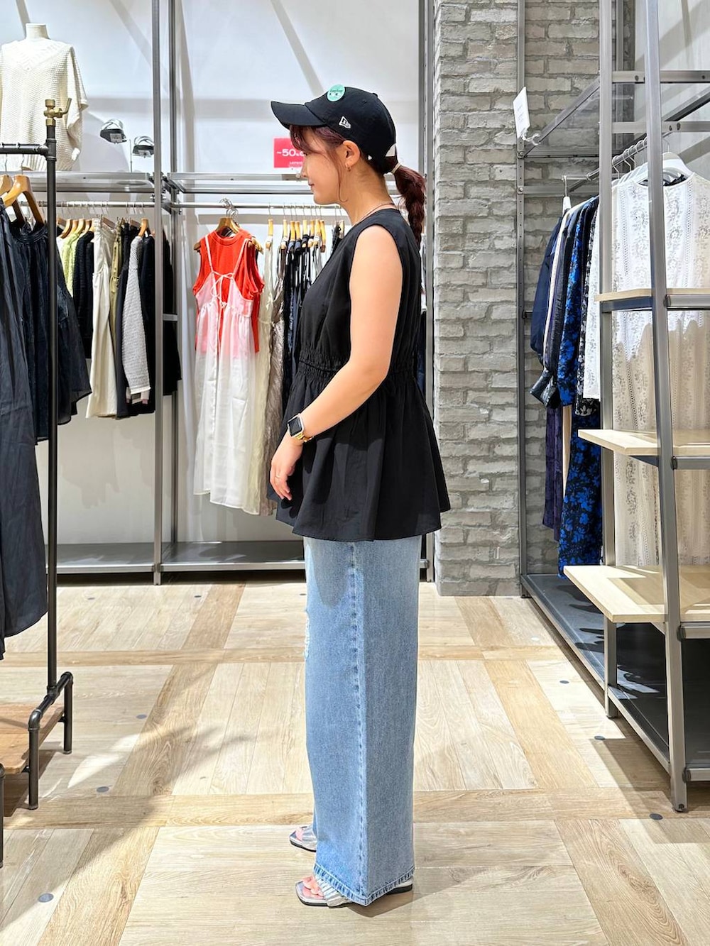 ブルー系のデニムパンツ、ブラック系のショルダーバッグ、グレー系のサンダルを着用したレディースの夏コーディネートの3枚目の写真