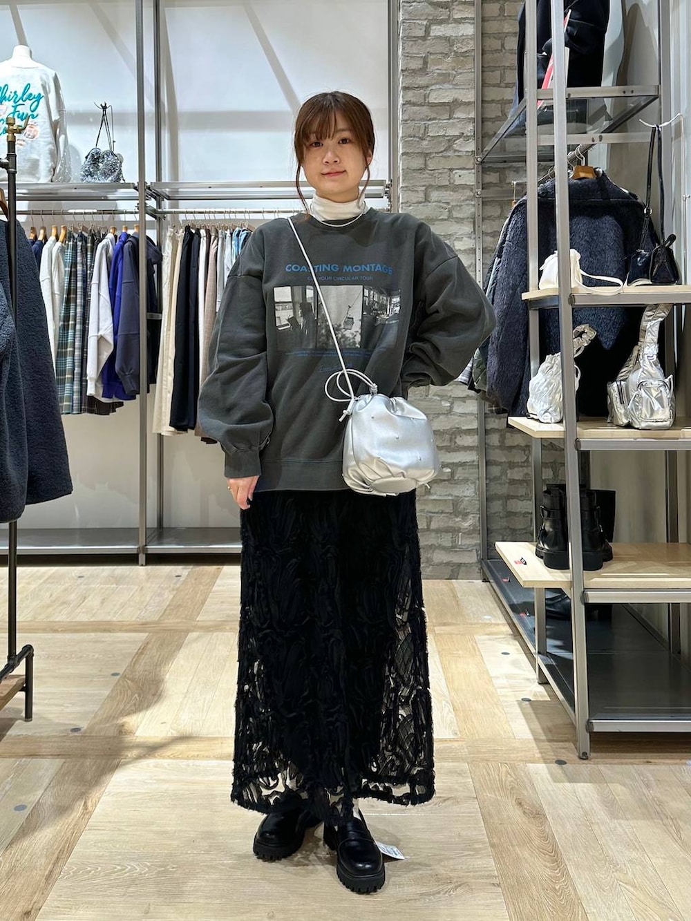 ブラック系のポンチョ、ブラック系のローファー、シルバー系のショルダーバッグを着用したレディースの冬コーディネートの4枚目の写真