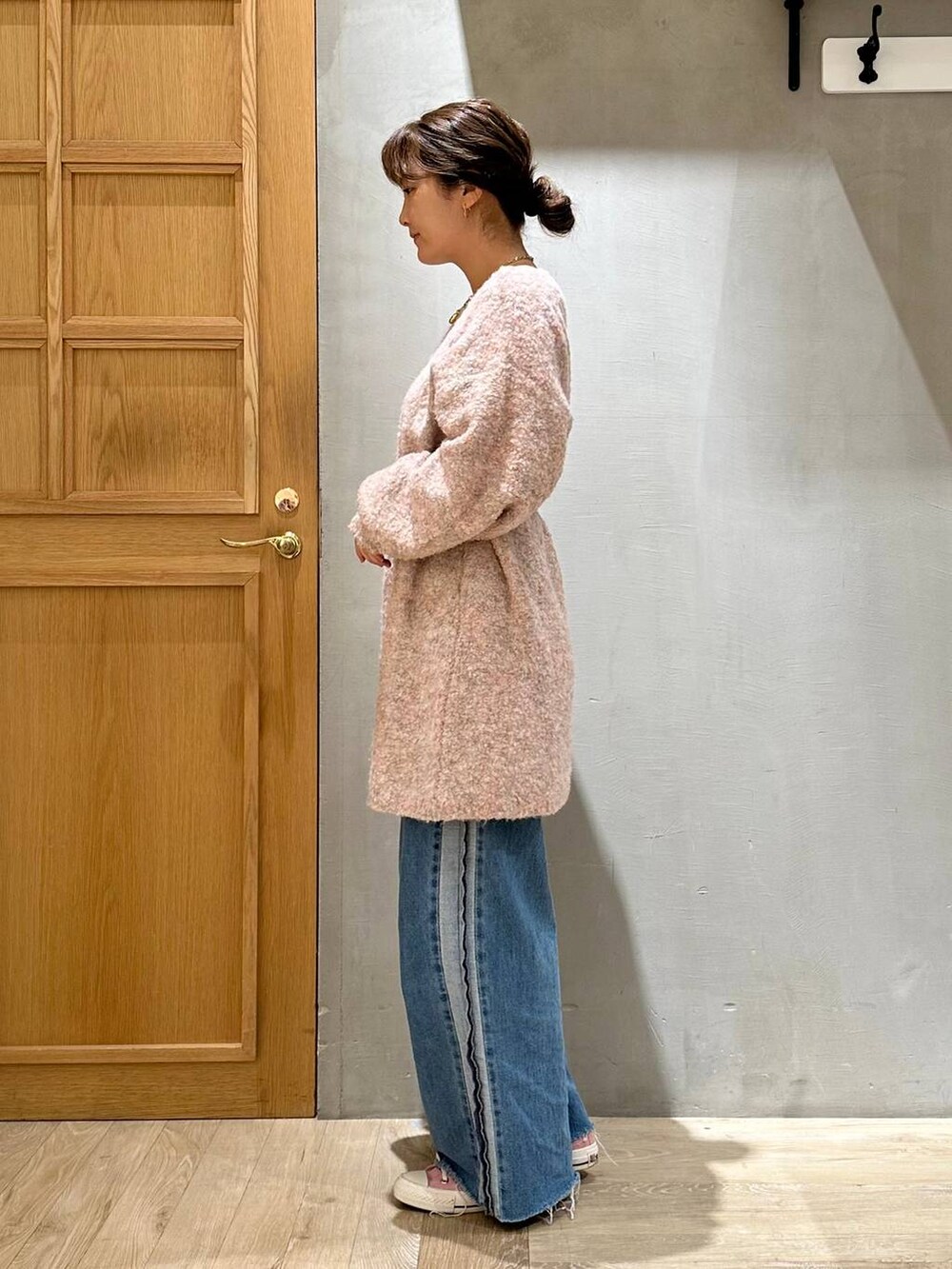 ピンク系のワンピース、ブルー系のデニムパンツ、ブラウン系のネックレスを着用したレディースの冬コーディネートの3枚目の写真