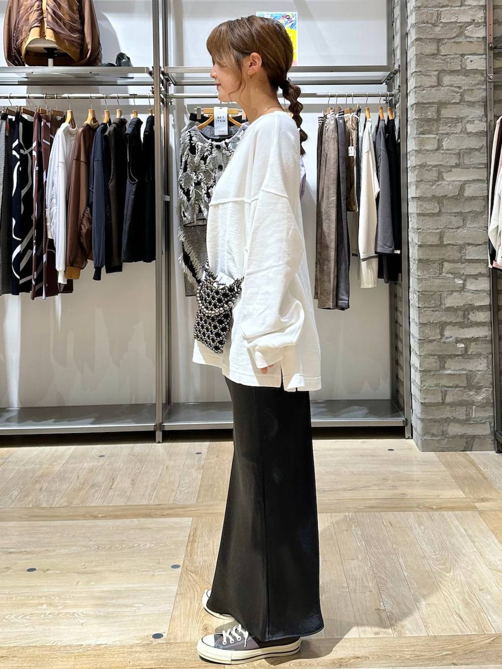 ブラック系のショルダーバッグ、ブラック系のスカート、ホワイト系のTシャツ/カットソーを着用したレディースの秋コーディネートの3枚目の写真