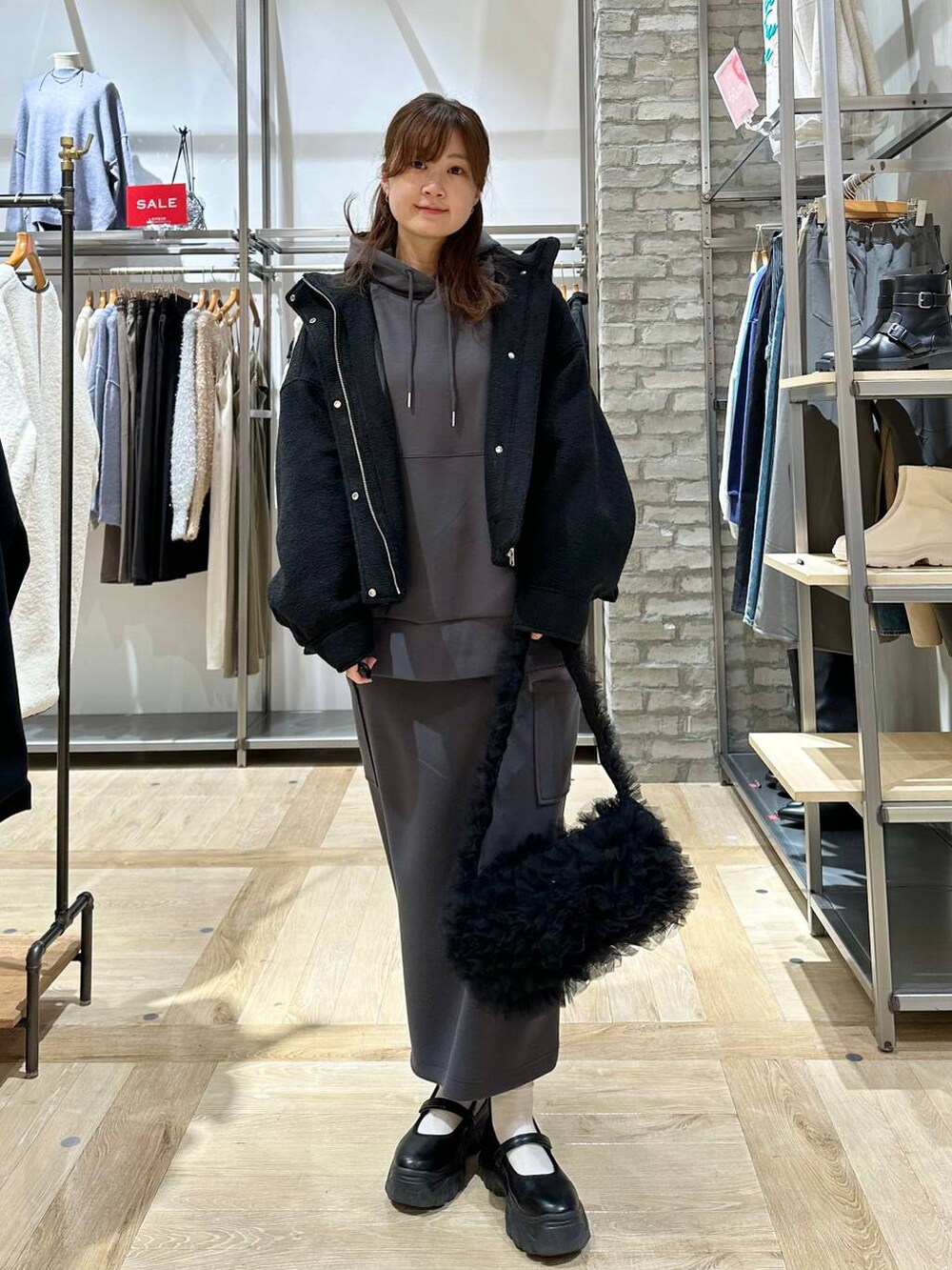 ブラック系のスニーカー、ブラック系のショルダーバッグ、グレー系のスカートを着用したレディースの冬コーディネートの4枚目の写真