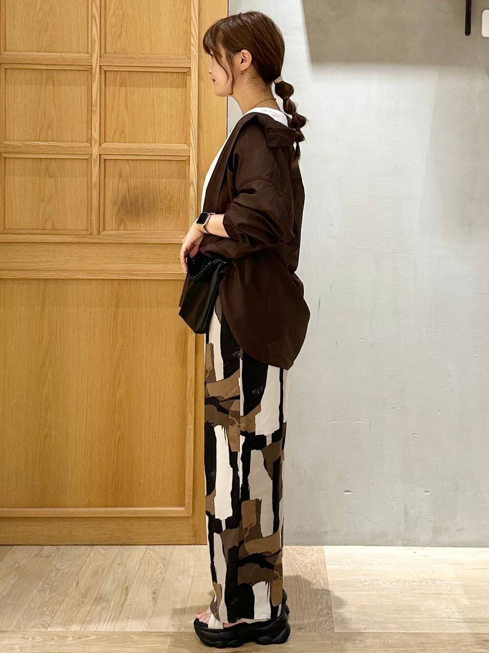 ベージュ系のその他パンツ、ホワイト系のサンダル、ブラック系のショルダーバッグを着用したレディースの夏コーディネートの3枚目の写真