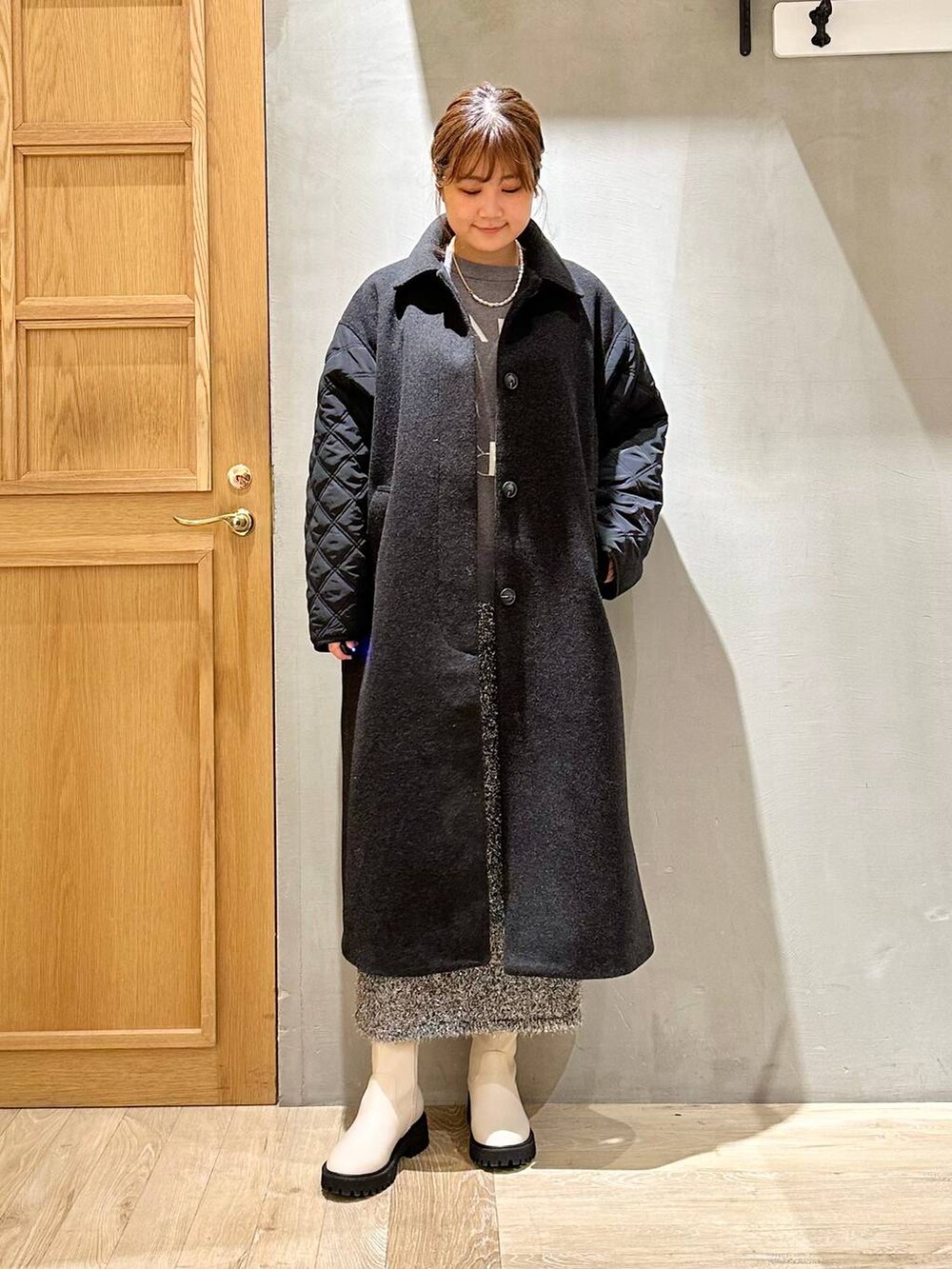 ホワイト系のブーツ、グレー系のニット/セーター、ブラック系のスカートを着用したレディースの冬コーディネートの5枚目の写真