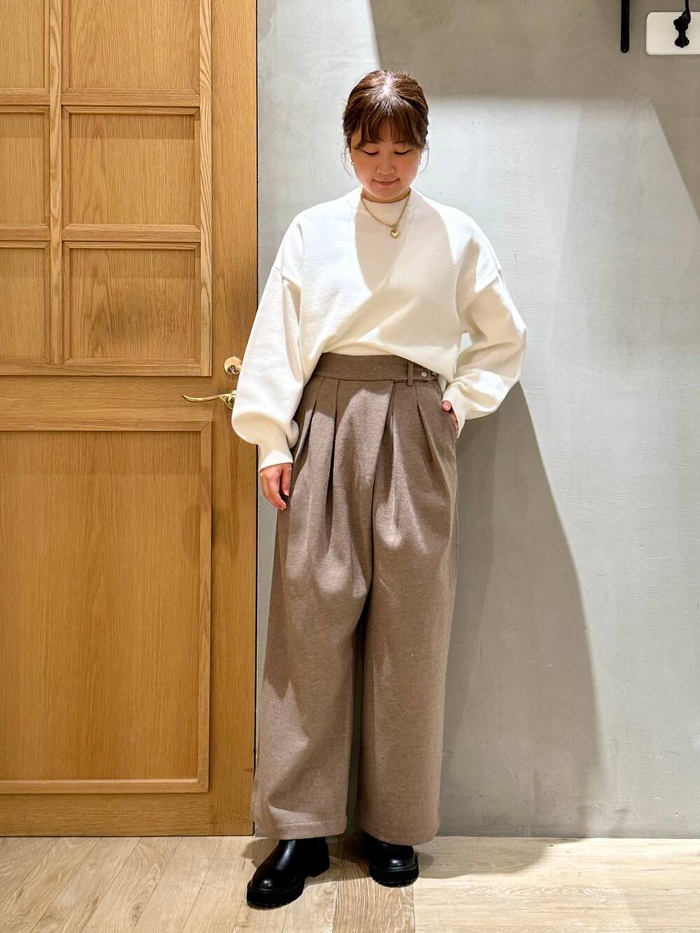 ベージュ系のショルダーバッグ、ブラック系のブーツ、ホワイト系のニット/セーターを着用したレディースの冬コーディネートの2枚目の写真