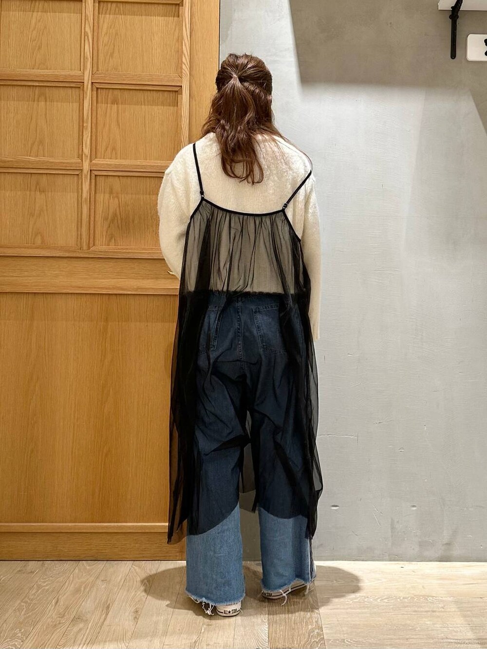 ブルー系のデニムパンツ、ホワイト系のニット/セーター、ブラック系のワンピースを着用したレディースの冬コーディネートの3枚目の写真