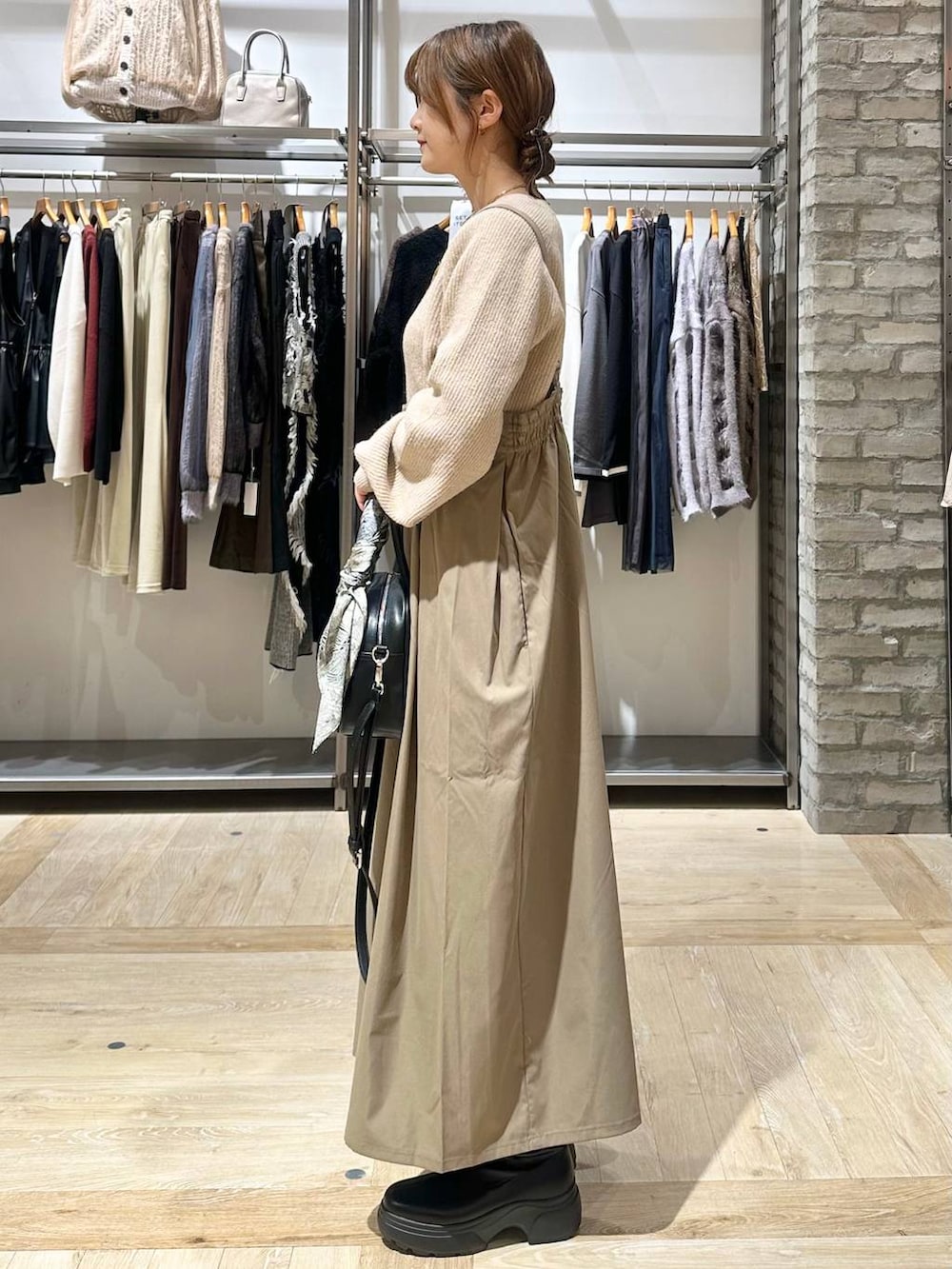 ベージュ系のニット/セーター、ブラック系のボストンバッグ、ブラック系のブーツを着用したレディースの秋コーディネートの3枚目の写真