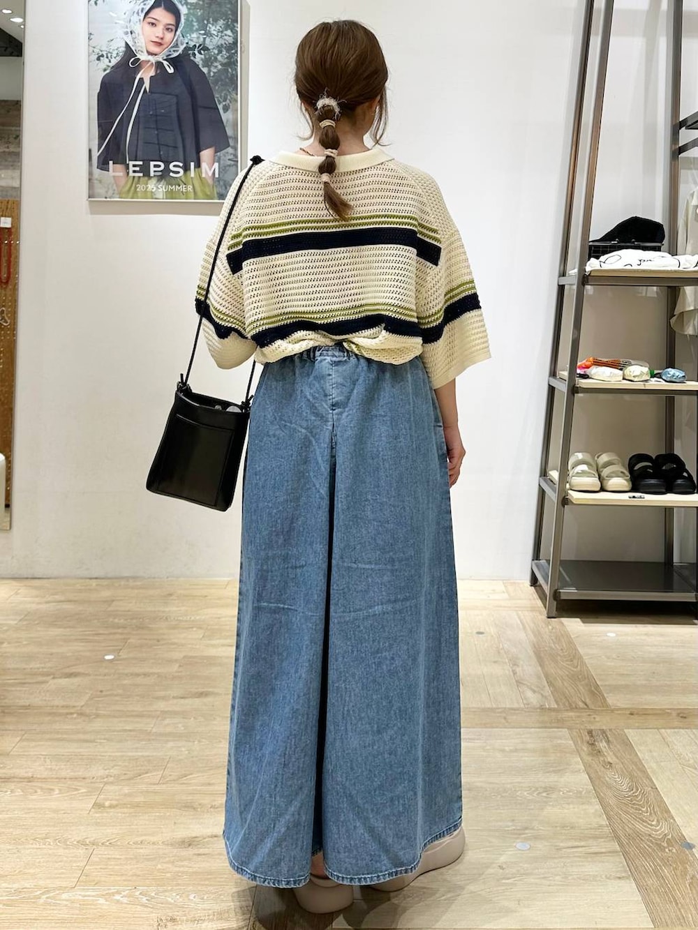 ブルー系のデニムパンツ、ベージュ系のサンダル、ブラック系のショルダーバッグを着用したレディースの夏コーディネートの3枚目の写真