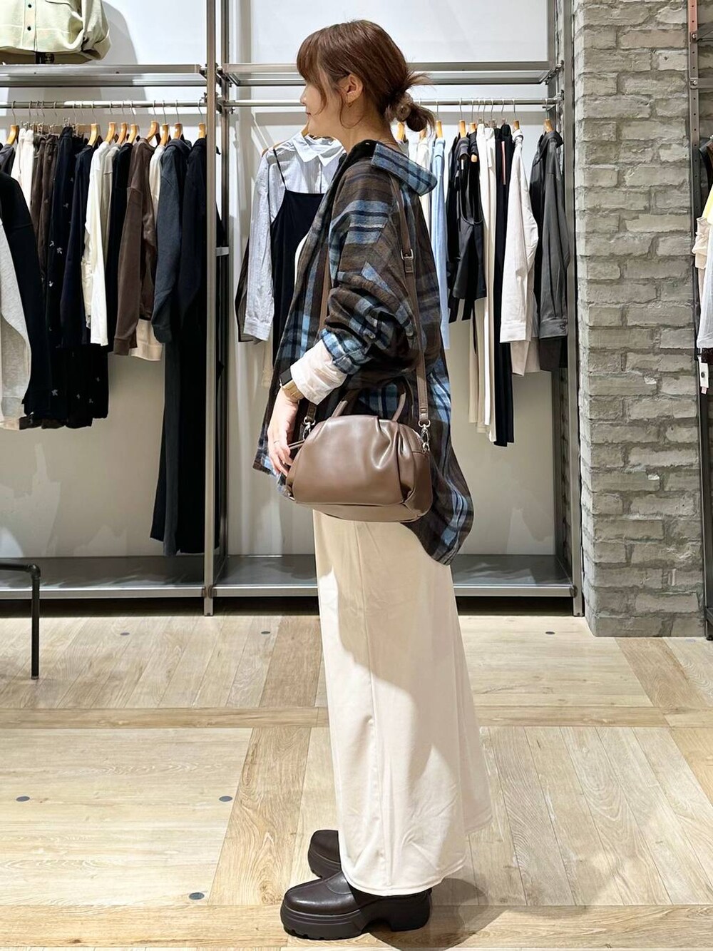ブラウン系のショルダーバッグ、ブラウン系のブーツ、ホワイト系のTシャツ/カットソーを着用したレディースの秋コーディネートの2枚目の写真
