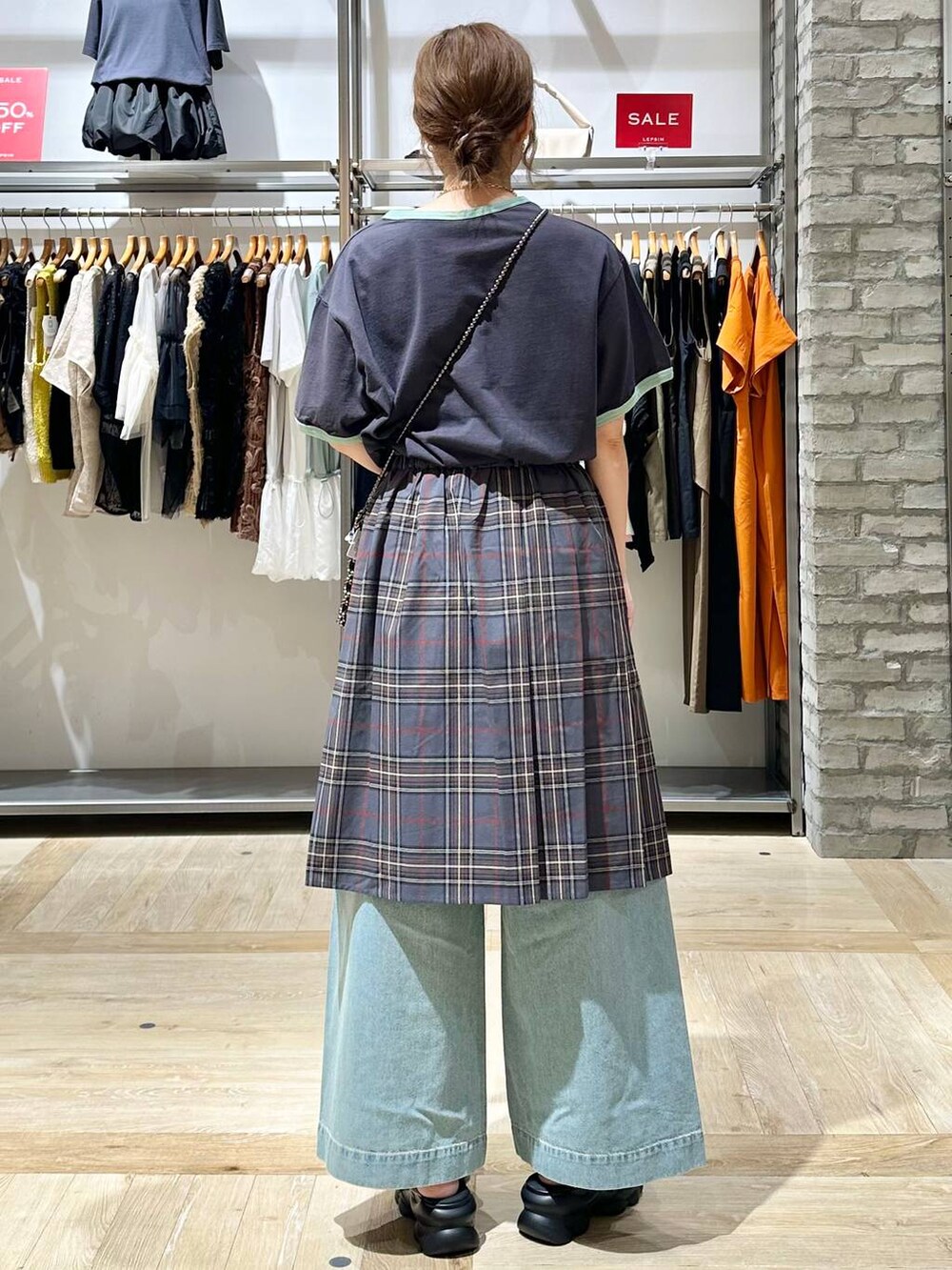 ブルー系のデニムパンツ、シルバー系のショルダーバッグ、ホワイト系のサンダルを着用したレディースの夏コーディネートの4枚目の写真