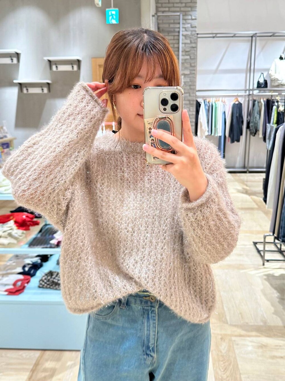 ブラック系のショルダーバッグ、ブルー系のデニムパンツ、ブラウン系のニット/セーターを着用したレディースの秋コーディネートの4枚目の写真