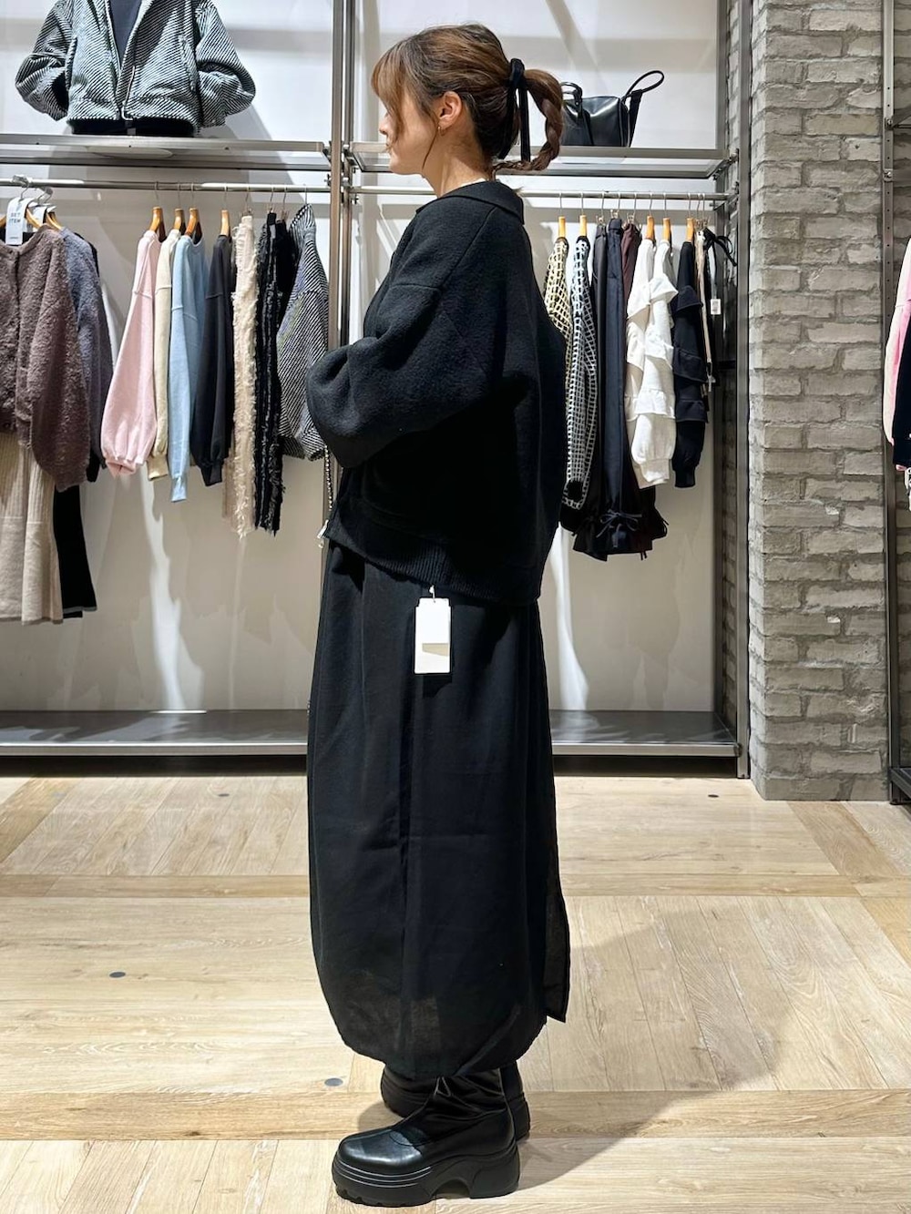 ブラック系のショルダーバッグ、ホワイト系のニット/セーター、ブラック系のブーツを着用したレディースの秋コーディネートの3枚目の写真