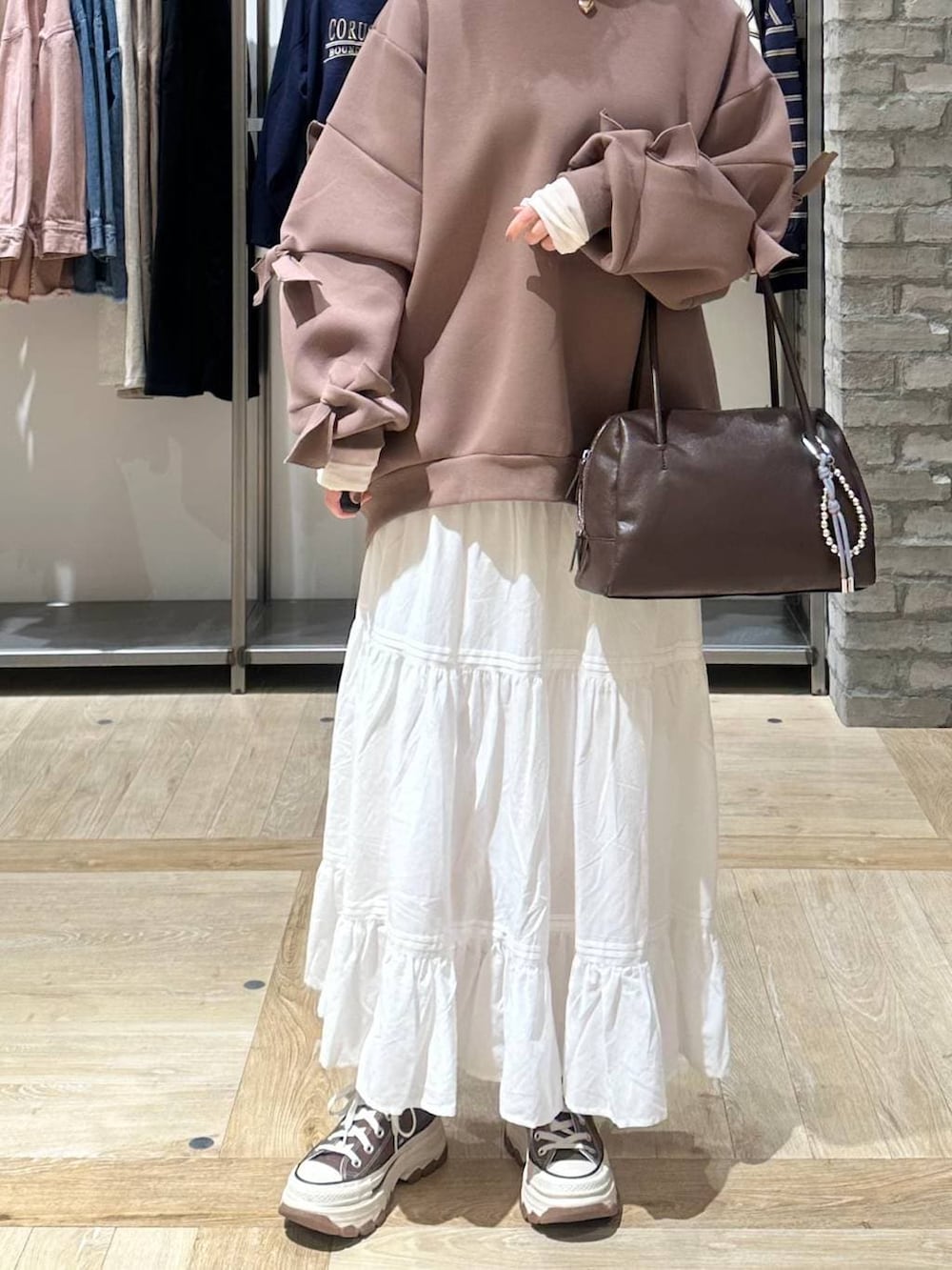 ブラウン系のスウェット、ホワイト系のTシャツ/カットソー、ブラック系のボストンバッグを着用したレディースの冬コーディネートの5枚目の写真