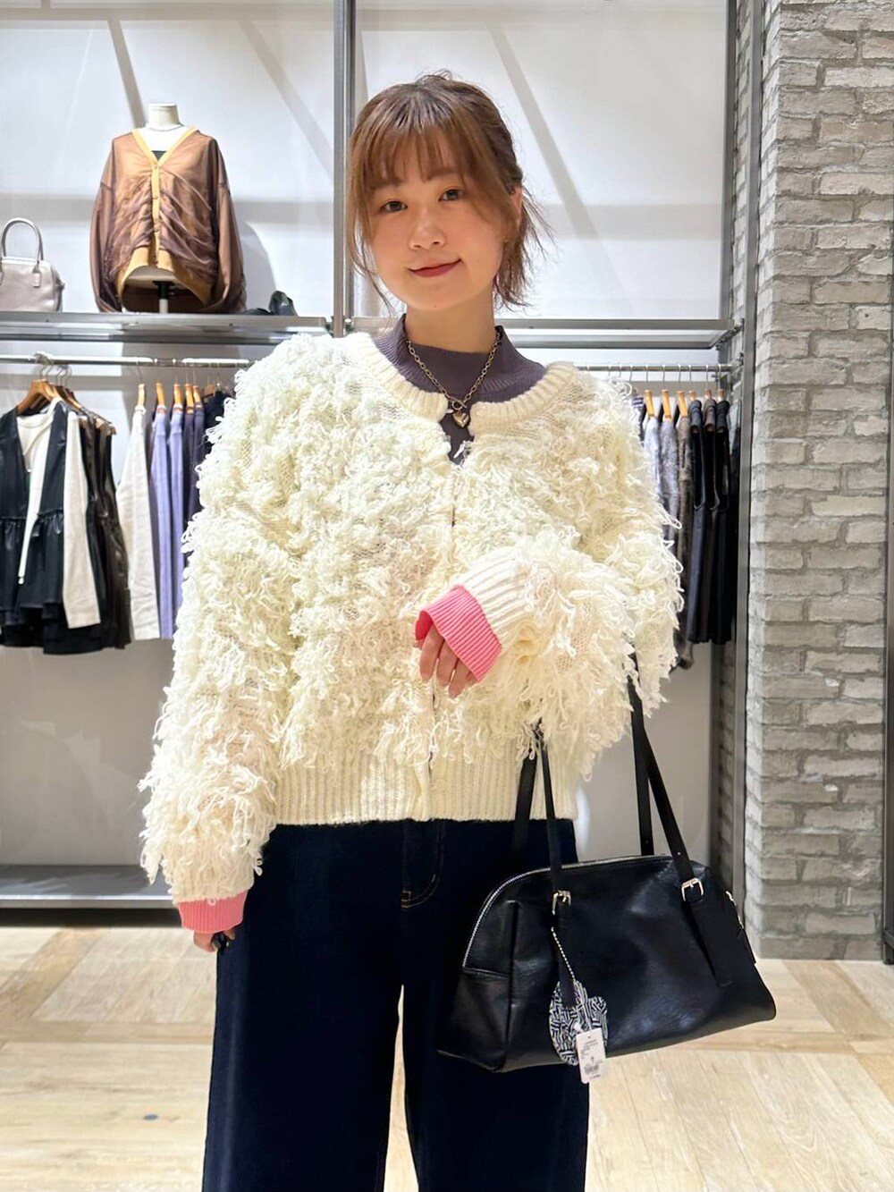 ブルー系のデニムパンツ、グレー系のニット/セーター、ブラック系のボストンバッグを着用したレディースの秋コーディネートの5枚目の写真