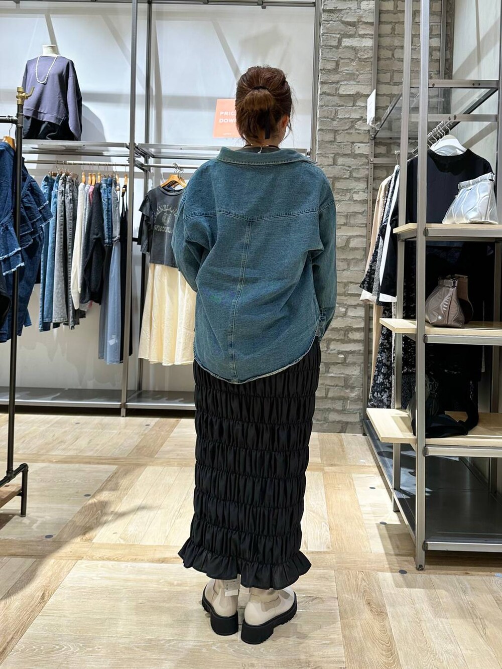 ブラック系のスカート、ホワイト系のブーツ、ブルー系のシャツ/ブラウスを着用したレディースの秋コーディネートの3枚目の写真